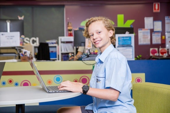 A student sits at a laptop in the library