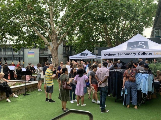 Parents meet with staff and uniform providers while students perform in the background