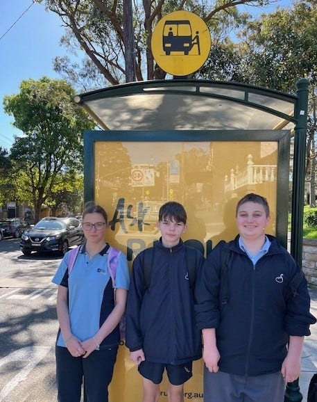 Three students wait at the bus stop