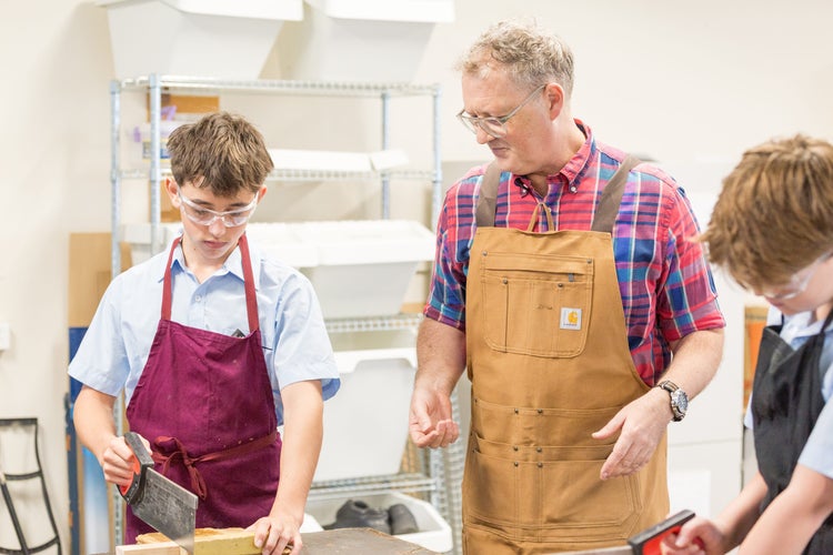 A teacher instructs students in woodwork
