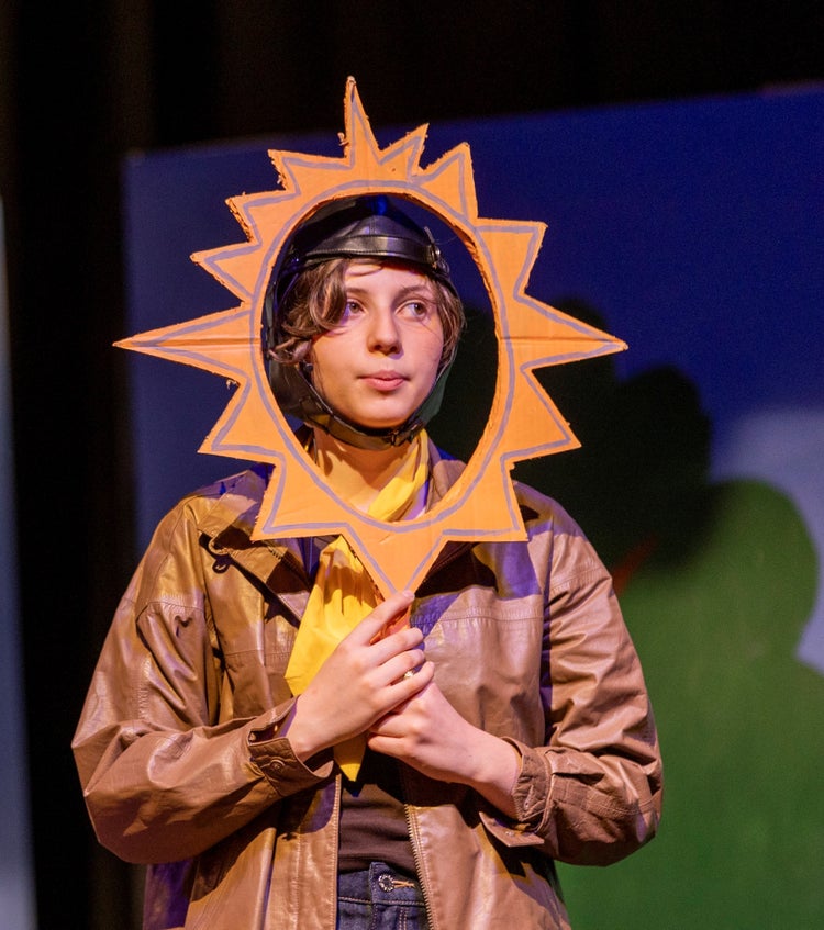 A student performing, she holds a fancy mirror over her face
