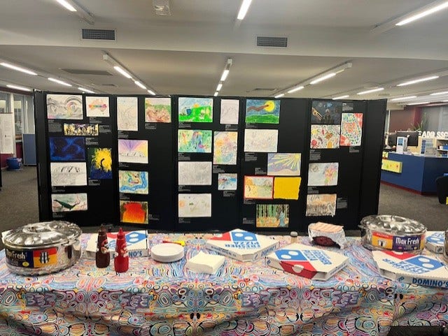 Student artwork is displayed behind a table of food at Pride Night.